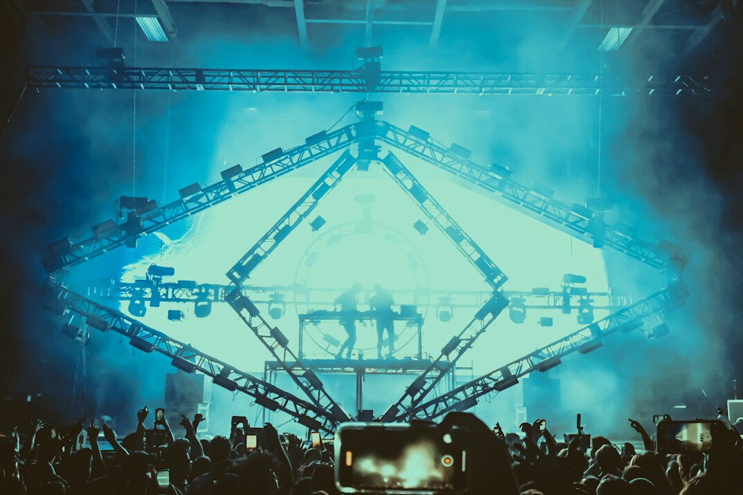 Live concert stage with big screens, lighting trusses and camera crane