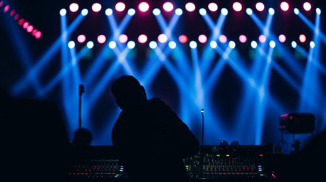Lighting console and DMX controller with colourful stage lights in the background